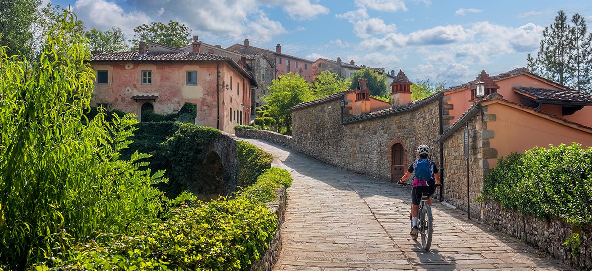 Donna che guida la sua mountain bike elettrica in un piccolo villaggio vicino a Laterina in Val D'Arno, Toscana, Italia
