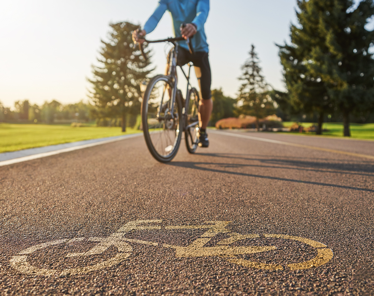 Ciclista professionista che guida una bici da strada su una pista ciclabile con disegnato su asfalto il simbolo di una bici