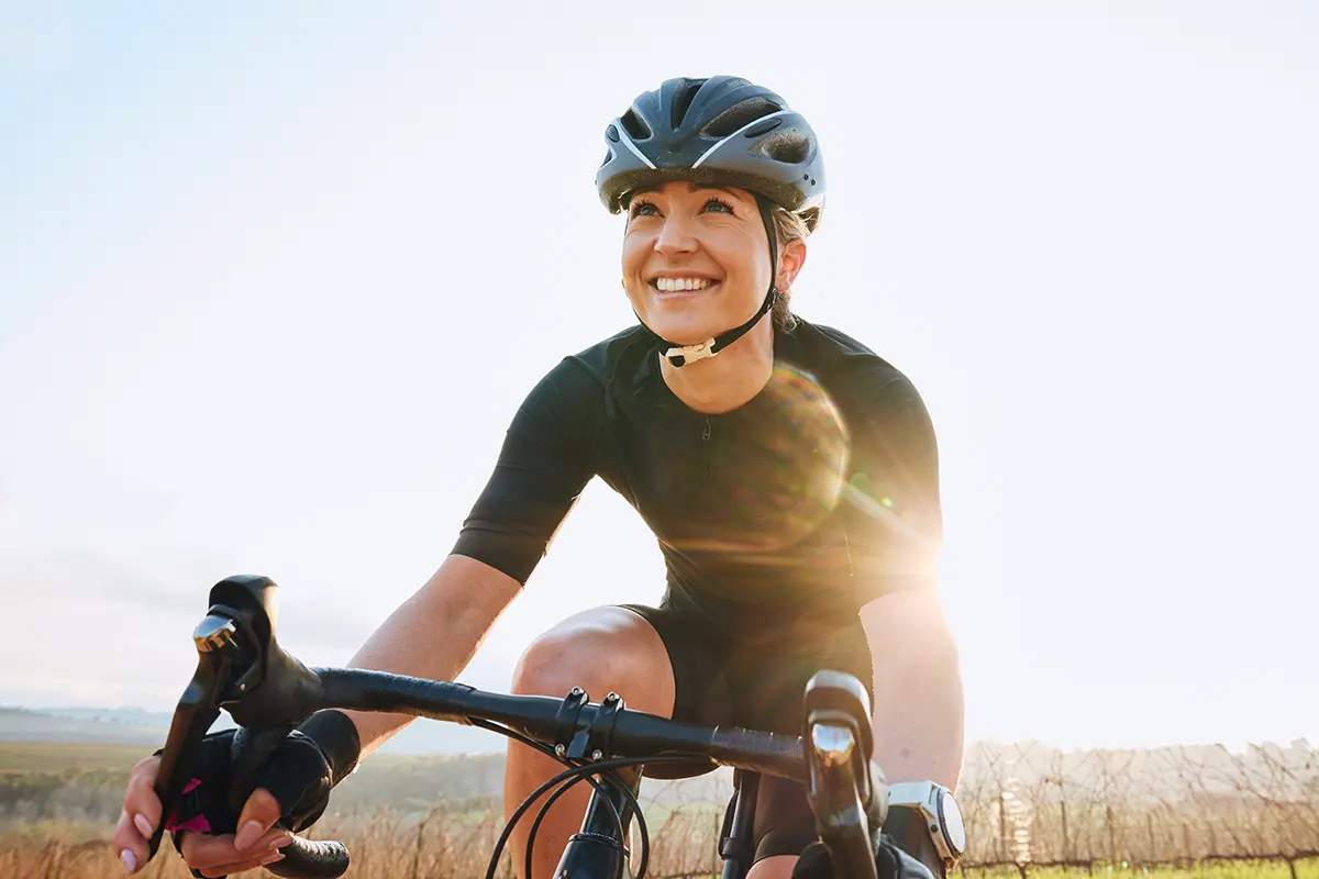 Ciclista donna che indossa una casco e va in bicicletta nella natura per avventure, viaggi e trasporti.