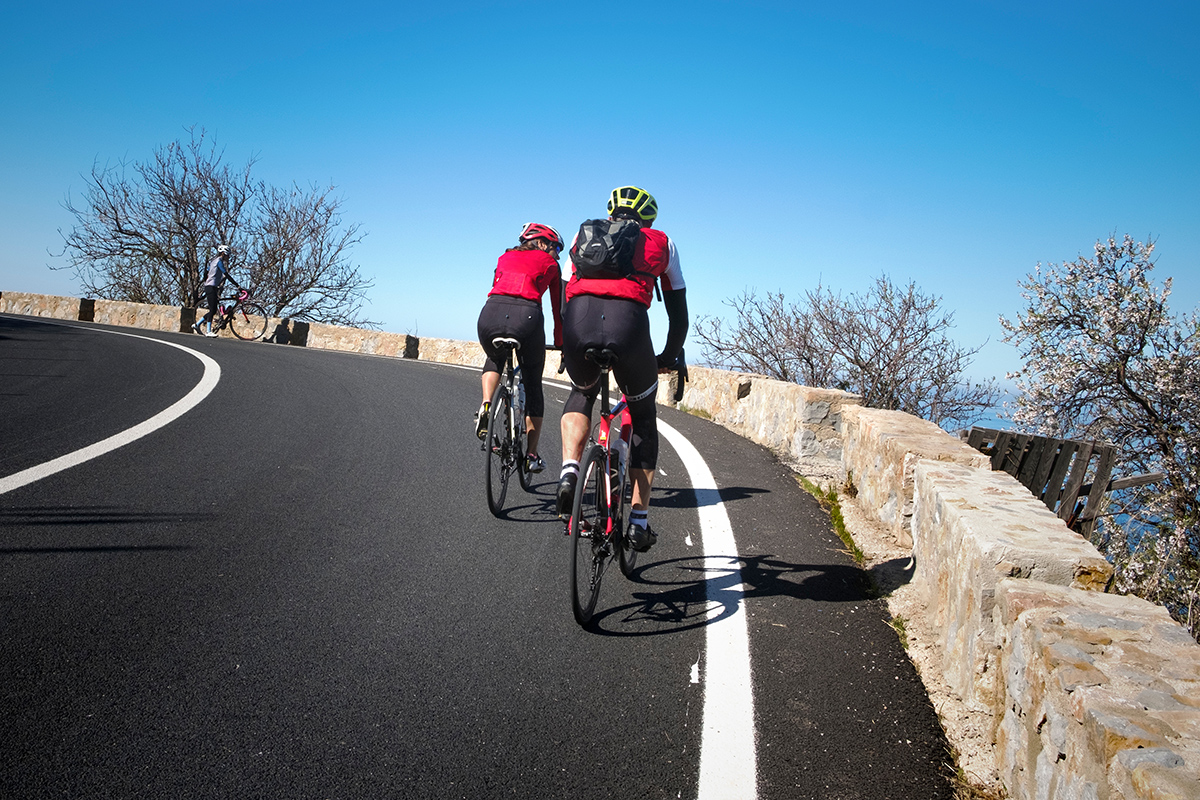 Coppia di ciclisti con una maglietta rossa che corre per le strade di Palma di Maiorca in una giornata di sole